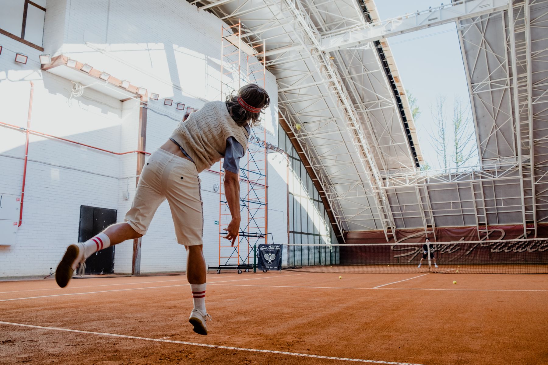 A tennis player preparing a serve on an indoor court