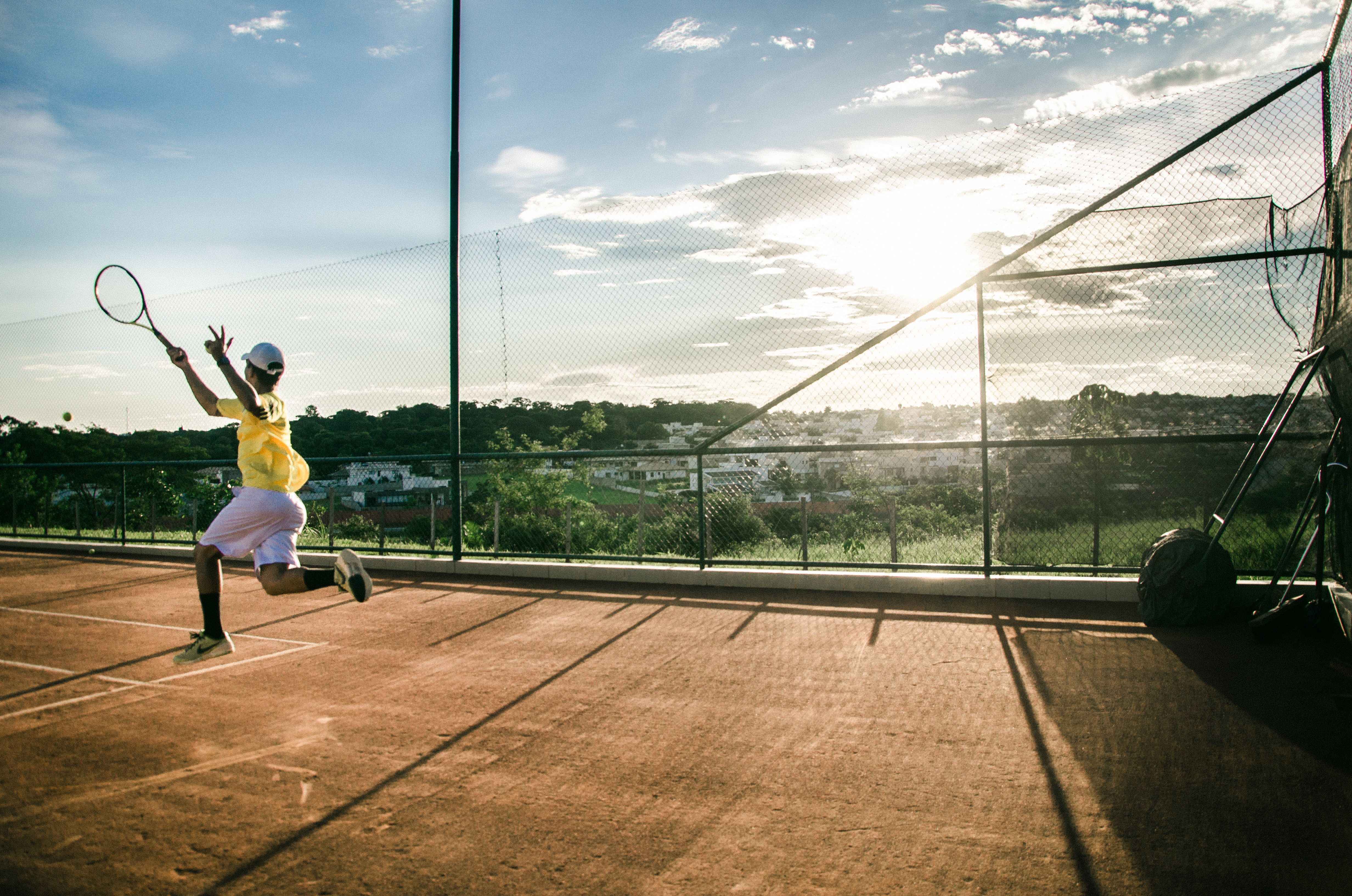 Tennis player serving on a sunlit outdoor court